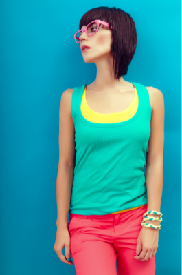 girl with bob haircut wearing brightly colors glasses, tank top, and pants