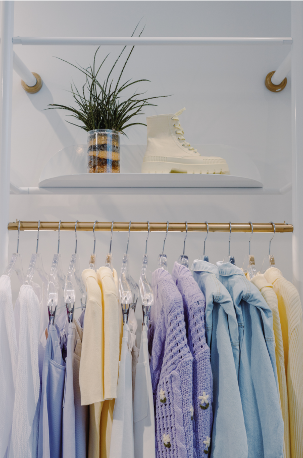 a closet rack with light summer women's wardrobe containing yellows, blues, and lavenders